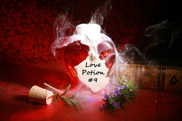 Ερωτικό φίλτρο. Μαγικό ξόρκι. LOVE Potion παρασκευάζεται από μια τσιγγάνα, μάγισσα, Fortune Teller, μάγισσα, Match Maker, Vixen, ή κάποιον που έχει σπουδάσει λευκή μαγεία ή τις σκοτεινές τέχνες. Πλήρης με ξόρκι αγάπης. Ένα φίλτρο αγάπης που καπνίζει από ένα μπουκάλι σε σχήμα καρδιάς. - Φωτογραφία, εικόνα