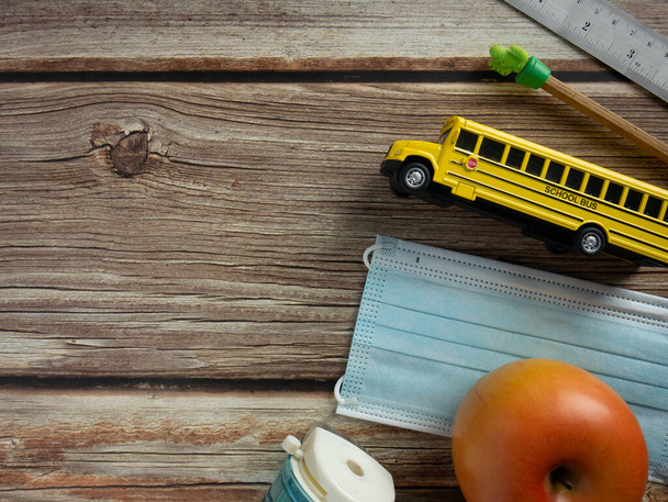 Lo scuolabus e la maschera sul tavolo di legno per l'istruzione o il concetto medico  - Foto, immagini