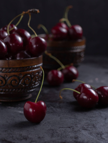 Organic juicy cherry in a bowl on dark background. Close-up photo, low key, selective focus - Foto, afbeelding