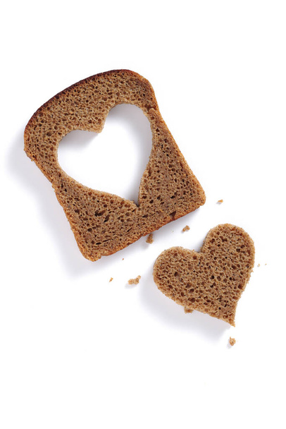 Slice of rye bread with a heart-shaped cut on white background, top view - Valokuva, kuva