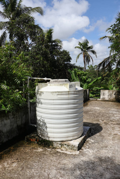 fehér hordó a tetőn tárolására és ellátására használt víz a ház egy vidéki területen - Fotó, kép