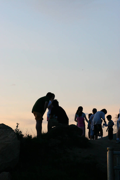 2 Július 2005 Egy csoport ember áll egy dombon a naplemente felett - Fotó, kép