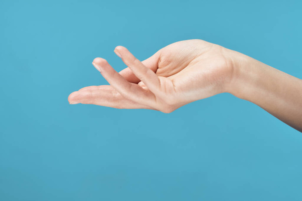 női kéz bőrápoló krém kék háttér közelkép - Fotó, kép