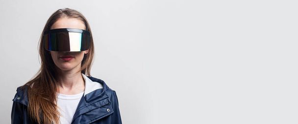 Young girl in virtual reality glasses in a blue jacket on a light background. Banner. - Fotoğraf, Görsel
