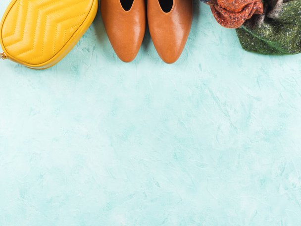 Fall pump shoes with autumn scarf and yellow handbag on turquoise background. Flat lay frame - Photo, Image