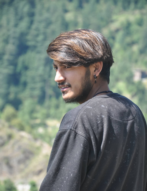 Un joven guapo del norte de la India de pie al aire libre con mirando hacia atrás  - Foto, Imagen