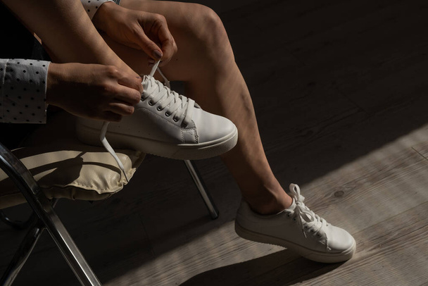 Woman put on new white leather sneakers - 写真・画像