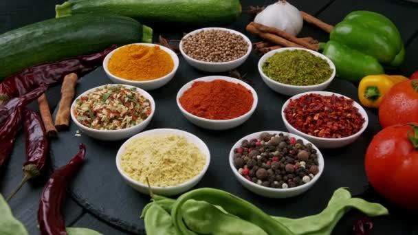 Colorful herbs and spices for cooking. Indian spices. On a black background. Top view - Footage, Video