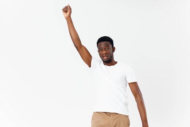 homem Africano aparência branco t-shirt segurar a mão acima de sua cabeça luz fundo - Foto, Imagem