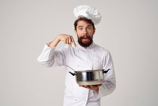 un hombre con ropa de chefs sosteniendo una cacerola en sus manos cocina trabajo de cocina - Foto, Imagen