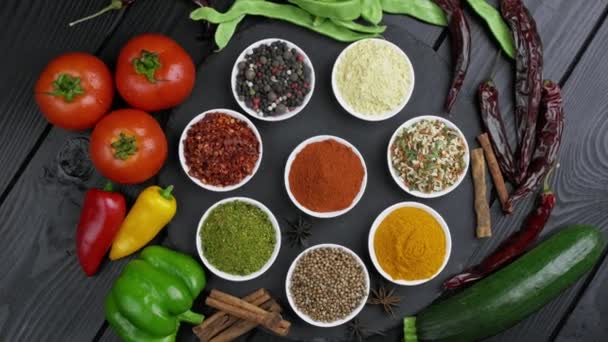 Värikkäitä yrttejä ja mausteita ruoanlaittoon. Intialaisia mausteita. Mustalla taustalla. Yläkuva - Materiaali, video