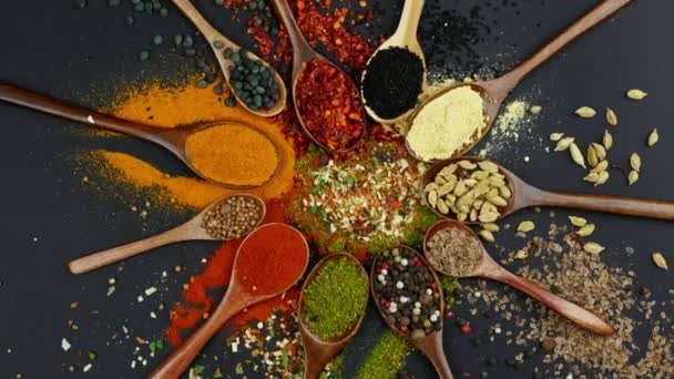 Dry colorful spices in spoons and bowls with fresh seasoning on dark background, top view - Footage, Video