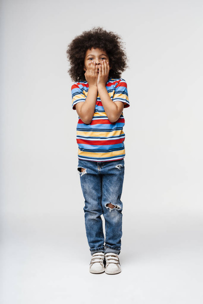Upset frowning little african boy in everyday clothes standing over wall background - Photo, Image