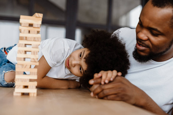 Black father and son playing with planks together at home - Fotó, kép