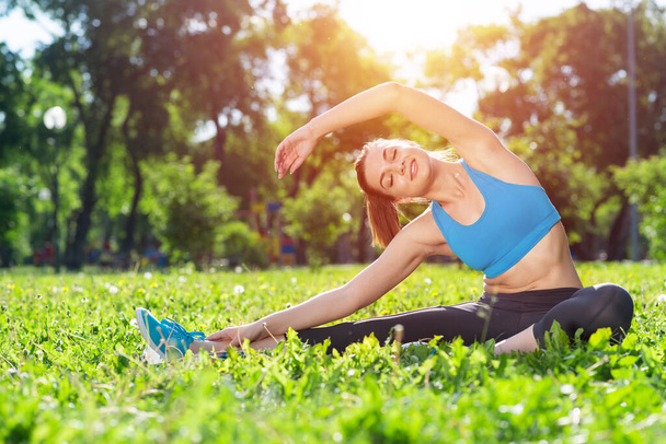 Attractive girl in sportswear doing yoga in park - Photo, Image