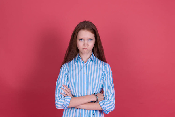 Pieni lapsi tyttö 13-vuotias sininen mekko eristetty vaaleanpunainen tausta katso kameraan vihainen katse ristissä kädet - Valokuva, kuva