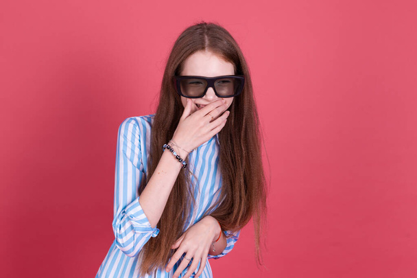 Menina criança 13 anos de idade em vestido azul com suportes isolados no fundo rosa vestindo óculos de cinema 3d feliz sorrindo rir - Foto, Imagem