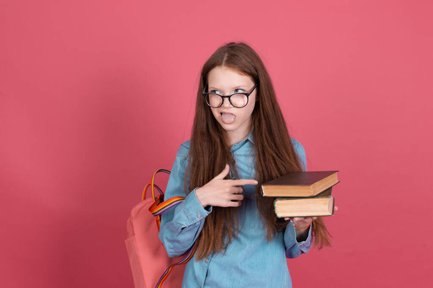 Little kid girl 13 years old isolated on pink background schoolgirl with backpack and books unhappy disappointed hate studying - Photo, Image