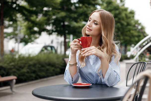 Young calm woman with coffee in cafe outdoor in city - Foto, Imagen