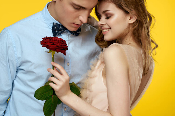 νεαρό ζευγάρι αγκαλιάζει ρομαντικό πάθος τριαντάφυλλο λουλούδι κίτρινο φόντο - Φωτογραφία, εικόνα
