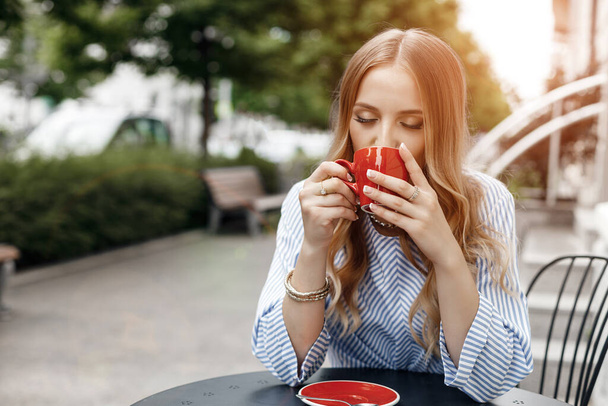 Young calm woman with coffee in cafe outdoor in city - Photo, image
