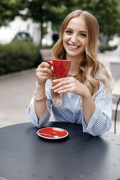 Young calm woman with coffee in cafe outdoor in city - Foto, Bild