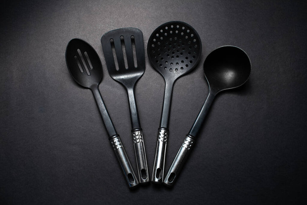 Studio picture of black plastic kitchen utensils with chromed handles. - Photo, Image
