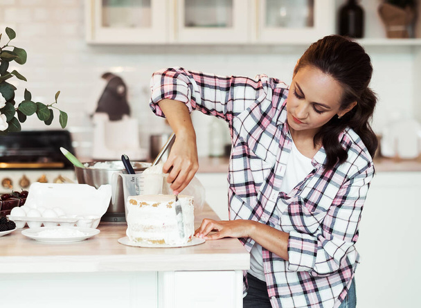 Lifestyle, cooking and freelance concept: Beautiful young woman cream cake layers. - Photo, Image