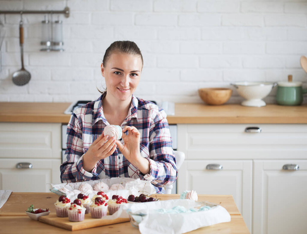 Young baker woman holding marshmallow. Happy, smiling and cheerful. - Photo, image