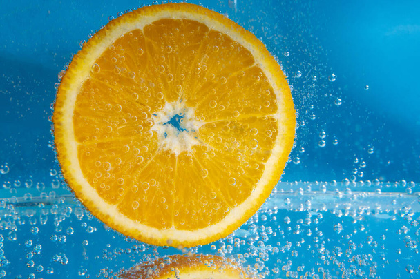 オレンジ色の果実を水中に閉じ込めます。さわやかなグレープフルーツドリンク、カクテル。スローモーション - 写真・画像