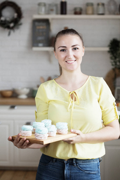 Young baker woman holding marshmallow. Happy, smiling and cheerful. - Φωτογραφία, εικόνα
