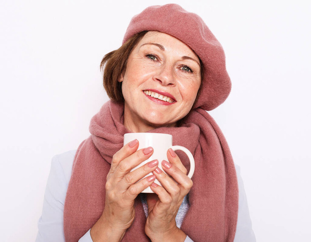 Portrait of senior woman wearing pink hat and scarf with cup of coffee - Foto, imagen