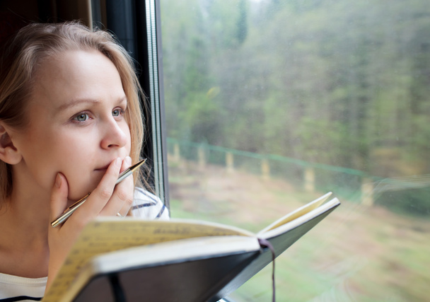 Mujer joven en un tren escribiendo notas
 - Foto, Imagen