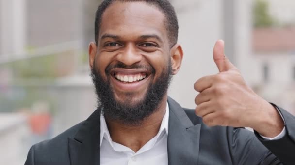 Millennial bearded black young male businessman boss showing thumb smiling demonstrates satisfaction praise. African American customer client satisfied with service quality expresses approval gesture - Footage, Video
