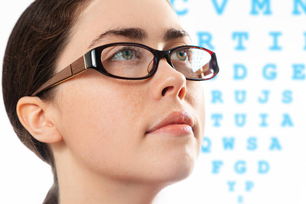 Terve näky. Lähikuva kasvot nuori kaunis nainen lasit katsomalla kaavio tarkistaa hänen visionsa. Käsite optinen testi ja silmätautien. - Valokuva, kuva
