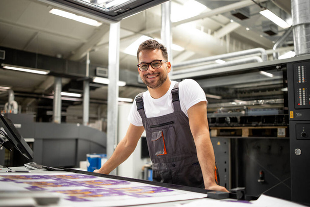 Retrato del trabajador en la sala de control comprobando la calidad de impresión en la imprenta. - Foto, Imagen