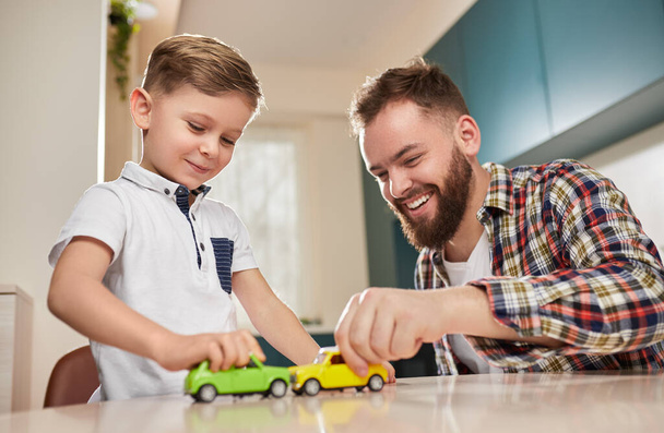 Cheerful father and son playing with toy cars - Fotó, kép