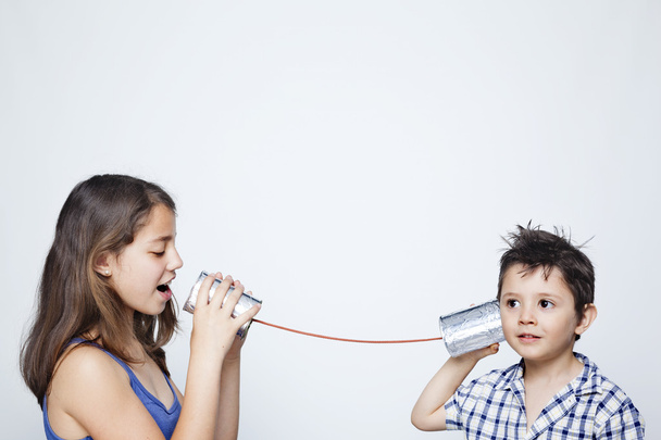 Kids using a can as telephone against gray background - Zdjęcie, obraz