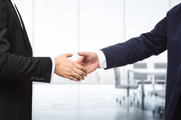Handshake of two businessmen on the background of bright boardroom, partnership concept, close up - 写真・画像