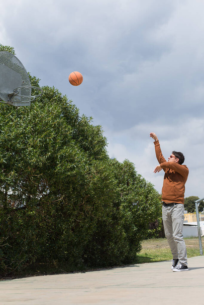 Стильный молодой человек играет с мячом на свежем воздухе - Фото, изображение