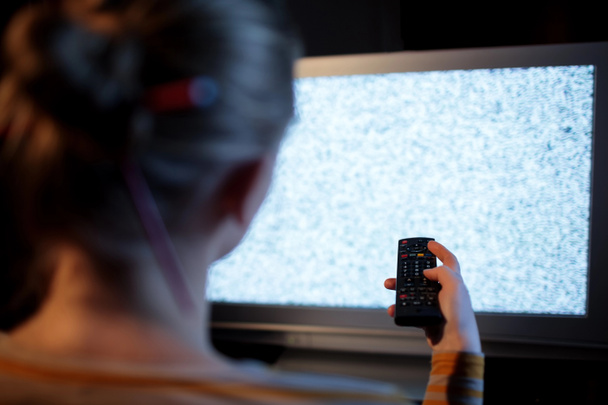 Mujer con mando a distancia delante del televisor
 - Foto, Imagen