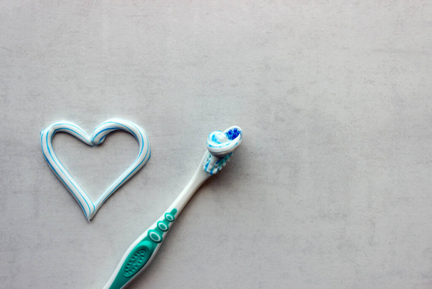 Uusi hammasharja ja sydämen muotoinen sininen ja valkoinen hammastahna. Työkalut henkilökohtaiseen suuhygieniaan. Käsitteet karieksen ehkäisy, hammaslääketiede. Kopioi tila. - Valokuva, kuva