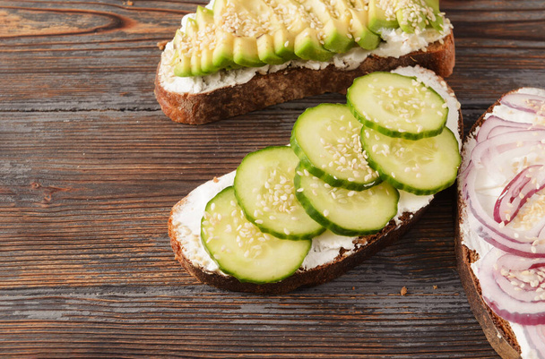 sandwiches with , cucumber , cheese and avocado slices, onion on a wooden close up - Fotoğraf, Görsel