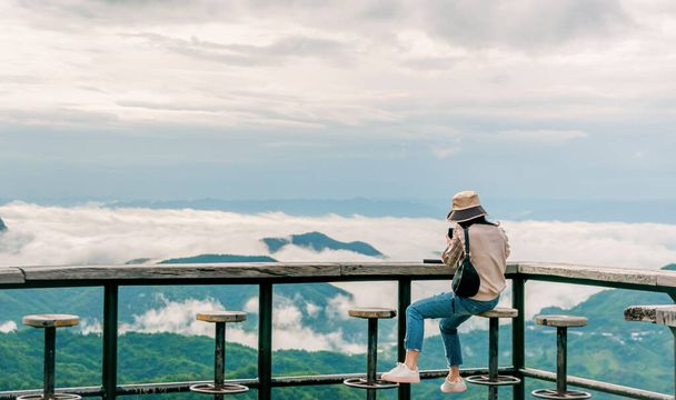 mujer sentada en balcón de madera mirando a la montaña y niebla ver viajes - Foto, imagen