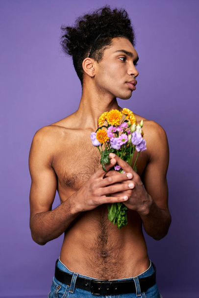 Transgender man with flowers on purple background. Handsome hispanic male with bouquet. Sexy athletic - Zdjęcie, obraz