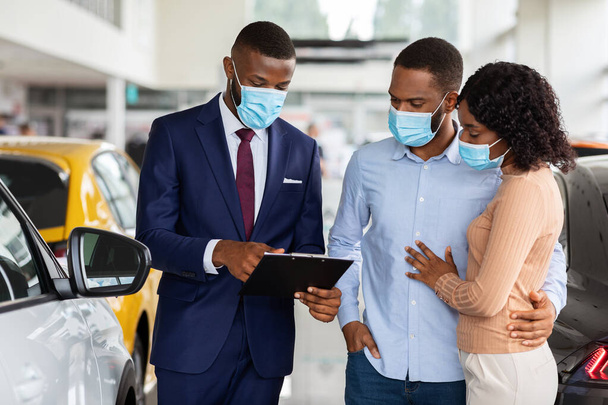 Salesperson In Medical Mask Consulting Black Spouses In Dealership Center - Photo, Image