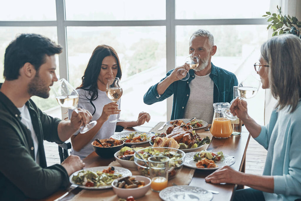 Modern multi-generation family drinking wine while having dinner together - Valokuva, kuva