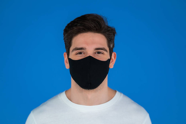 Portrait of handsome man in facial medical mask looking to camera. Guy in studio on bright purple background. Covid-19, coronavirus, new reality concept. - Foto, immagini