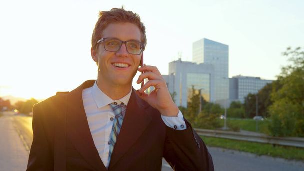 CHIUDI: Giovane uomo d'affari fiducioso che parla su smartphone mentre torna a casa a piedi. - Foto, immagini