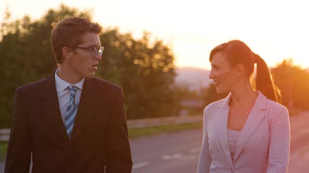 ЗАКРЫТИЕ UP: Веселые мужчина и женщина в формальной одежде идут на работу с восходом солнца
. - Фото, изображение